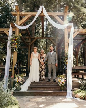 An outdoor wedding ceremony setup with white draping and wooden beams in a forest setting.