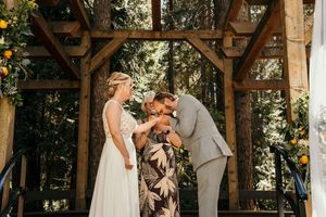 Rustic wooden pavilion decorated for an outdoor wedding celebration with natural greenery.