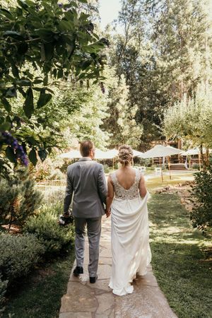 Wedding party walking along garden pathway on sunny afternoon.