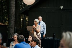 Guests mingling at an outdoor wedding reception with white paper lanterns and dark wood backdrop.