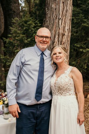 A couple poses together in a wooded outdoor setting for their wedding photos.