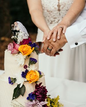 Colorful wedding bouquet with yellow, purple, and white flowers displayed on a white tablecloth.