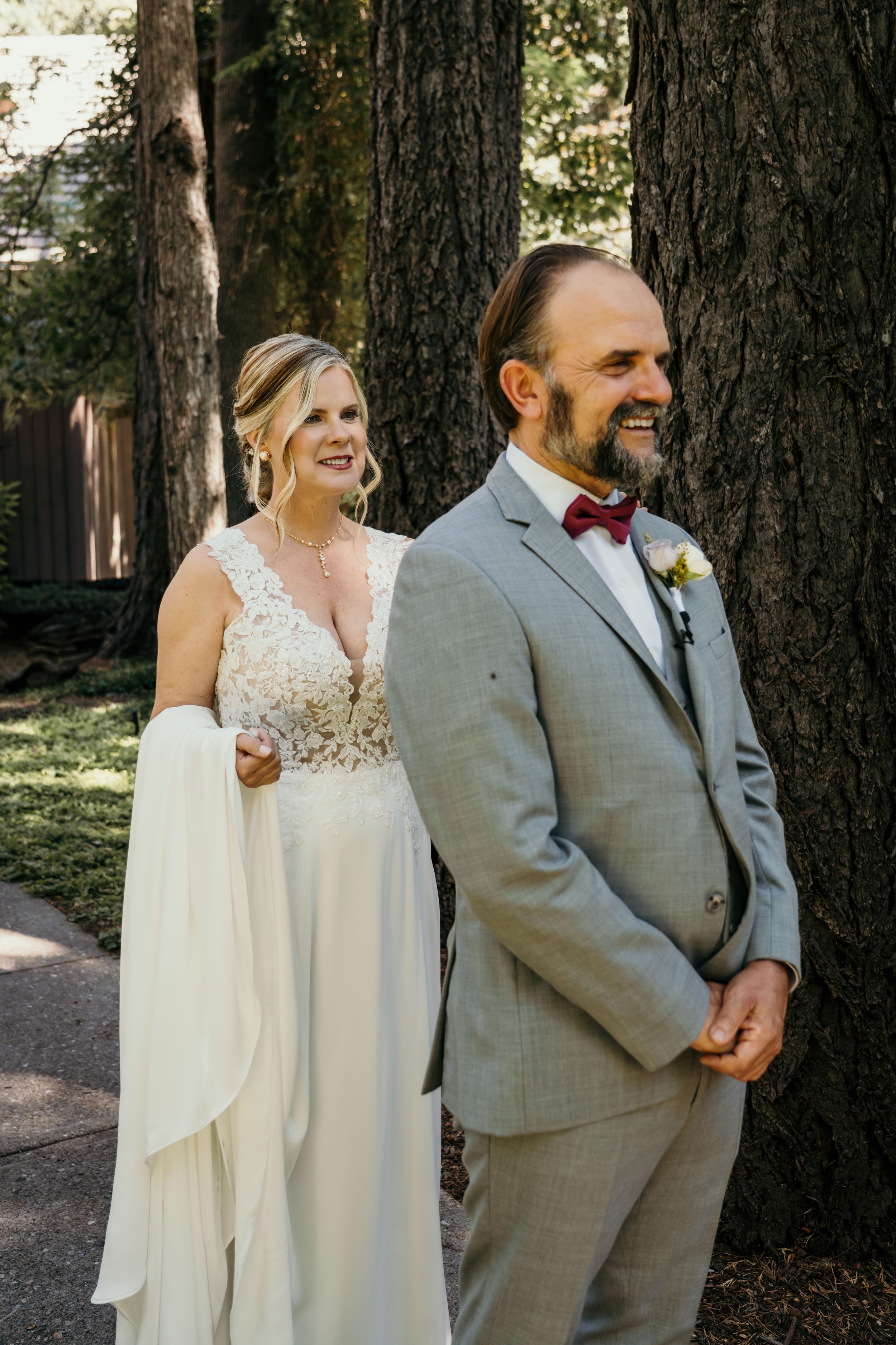 Wedding party poses against tall trees in a woodland setting.