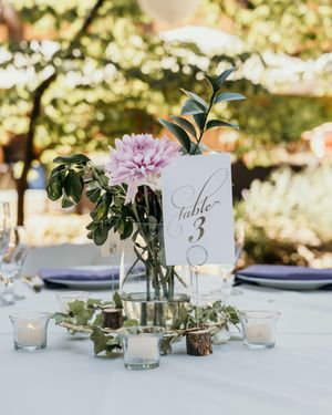 Elegant wedding table settings with numbered cards, greenery, and candlelight create a romantic outdoor atmosphere.