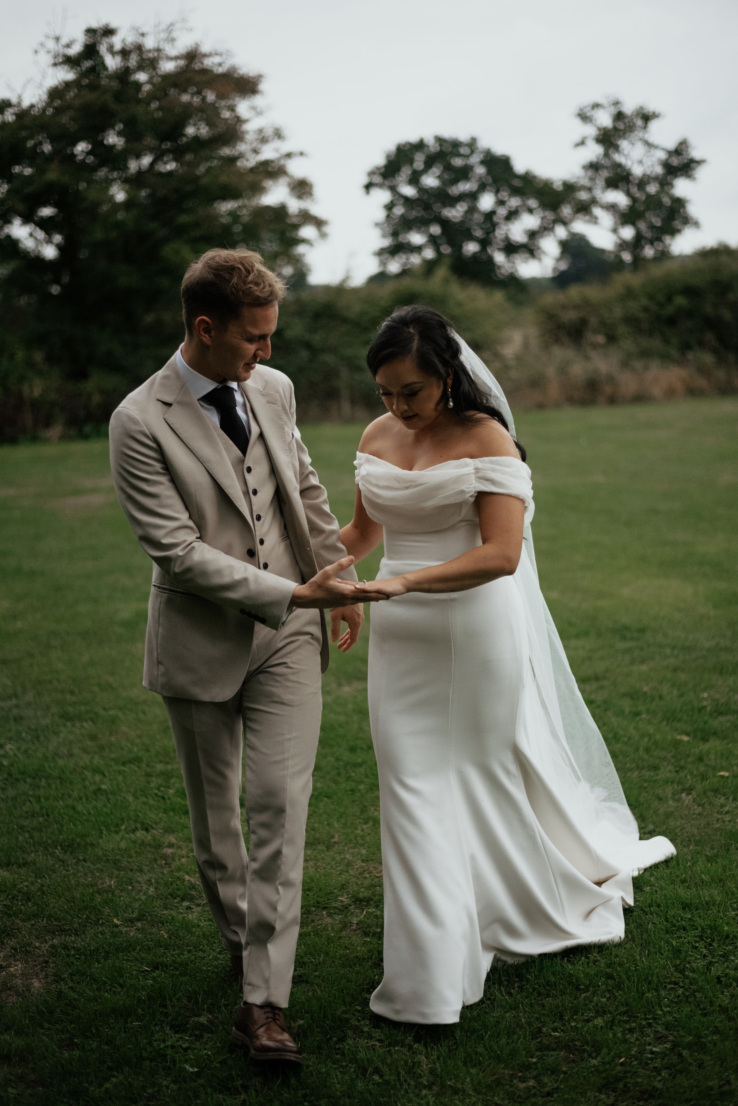 Playful newlywed couple dancing together on green lawn.