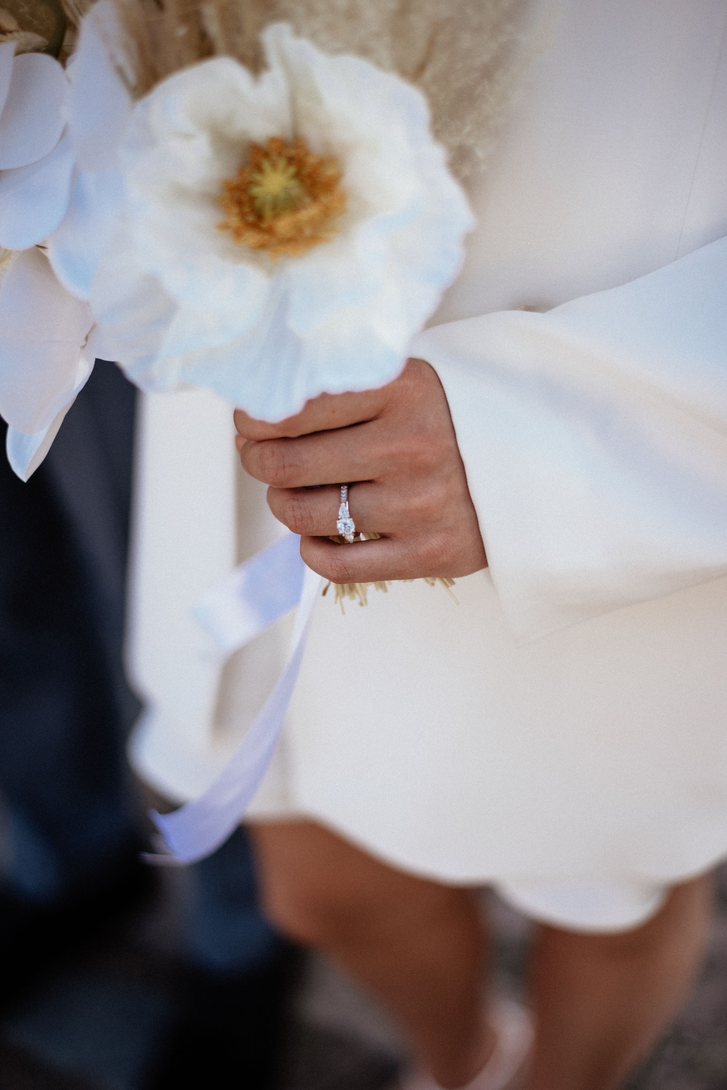 Elegant engagement ring detail shot with white flowers.