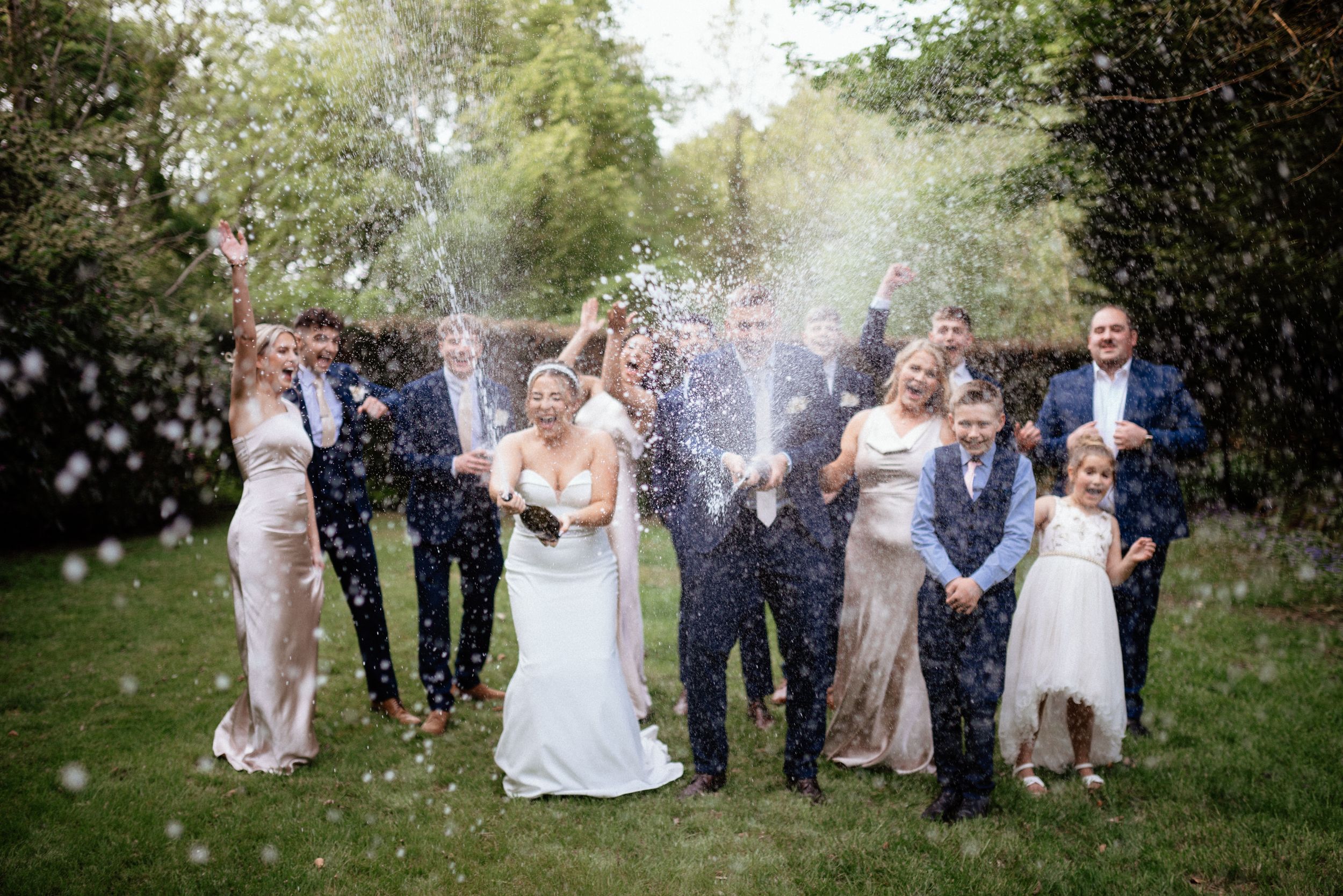 Wedding party celebrating with confetti in a garden setting.