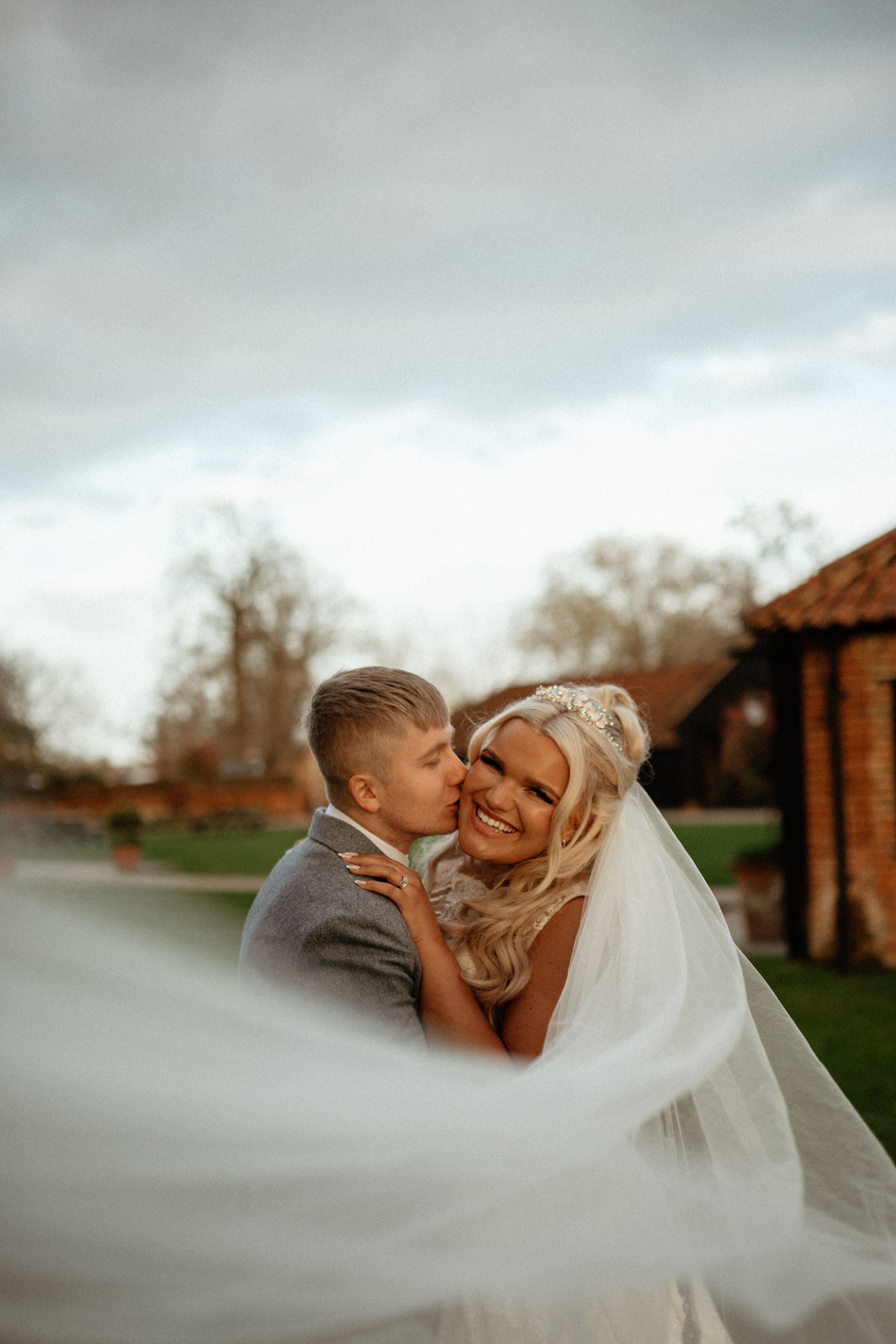 Dramatic wedding veil shot captures romantic moment between newlyweds.