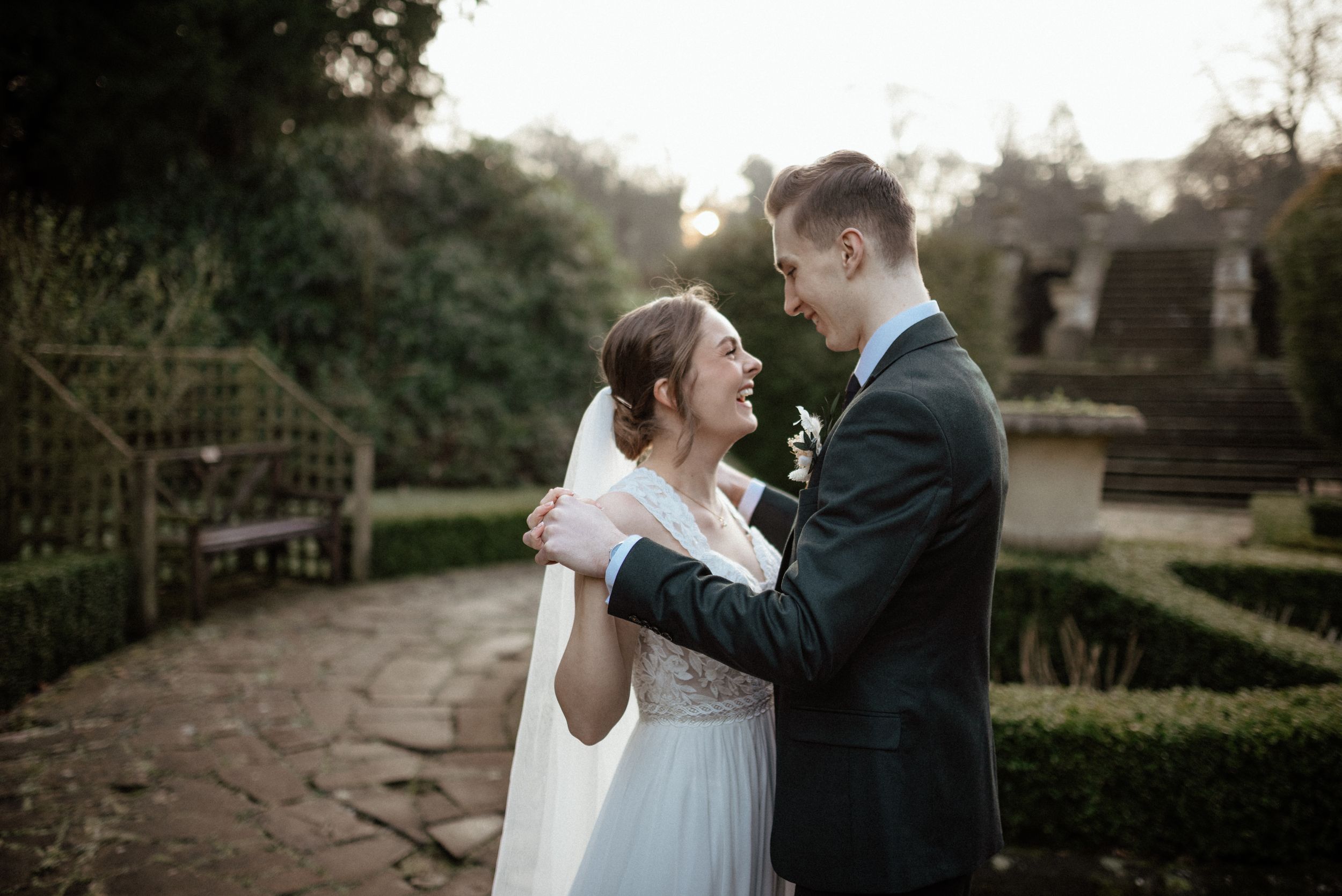 Romantic wedding couple shares intimate moments in a garden setting at sunset.