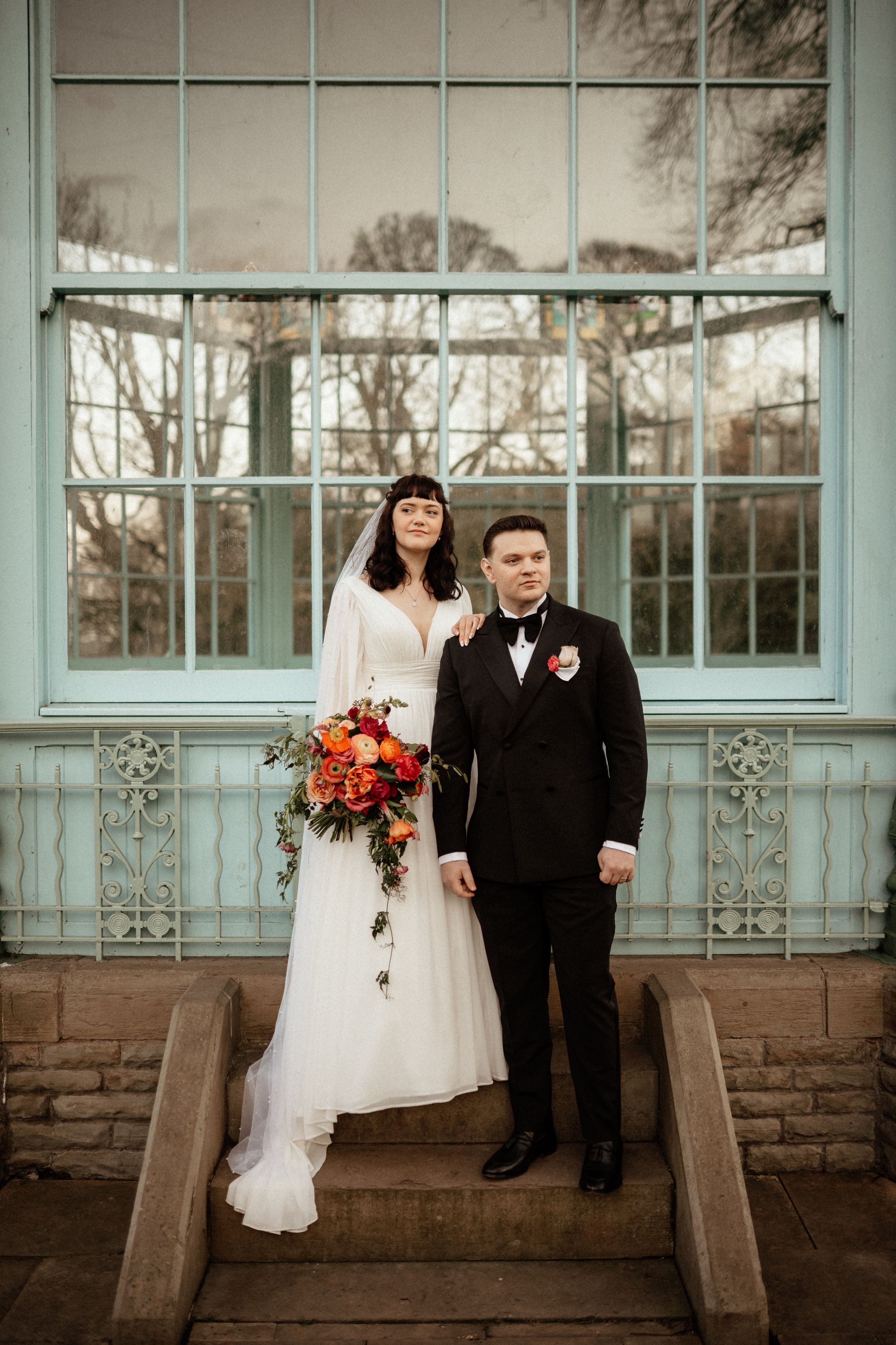 Wedding portrait session in front of a vintage glass conservatory building.