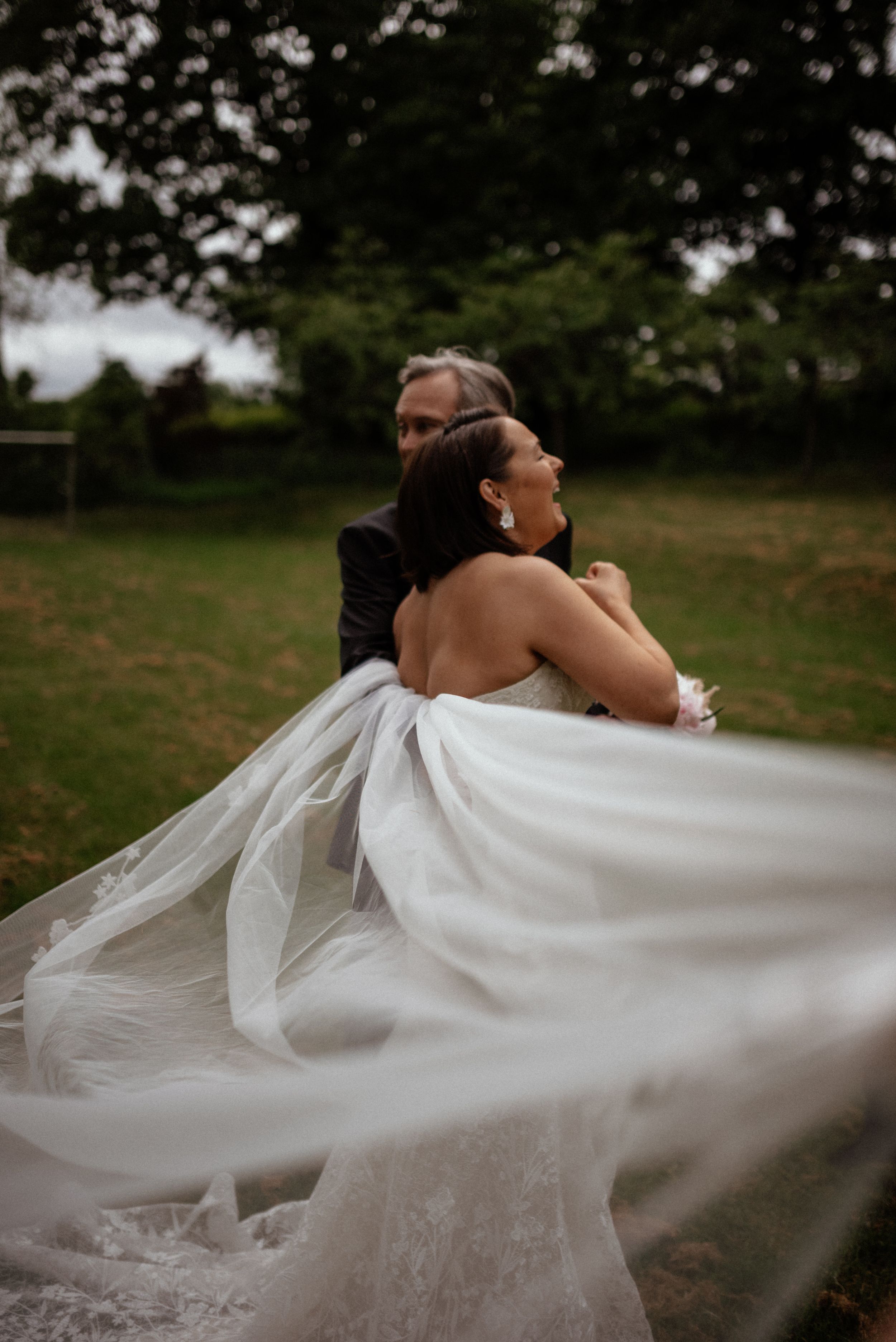 Wedding veil flowing dramatically in the wind during outdoor portrait session.