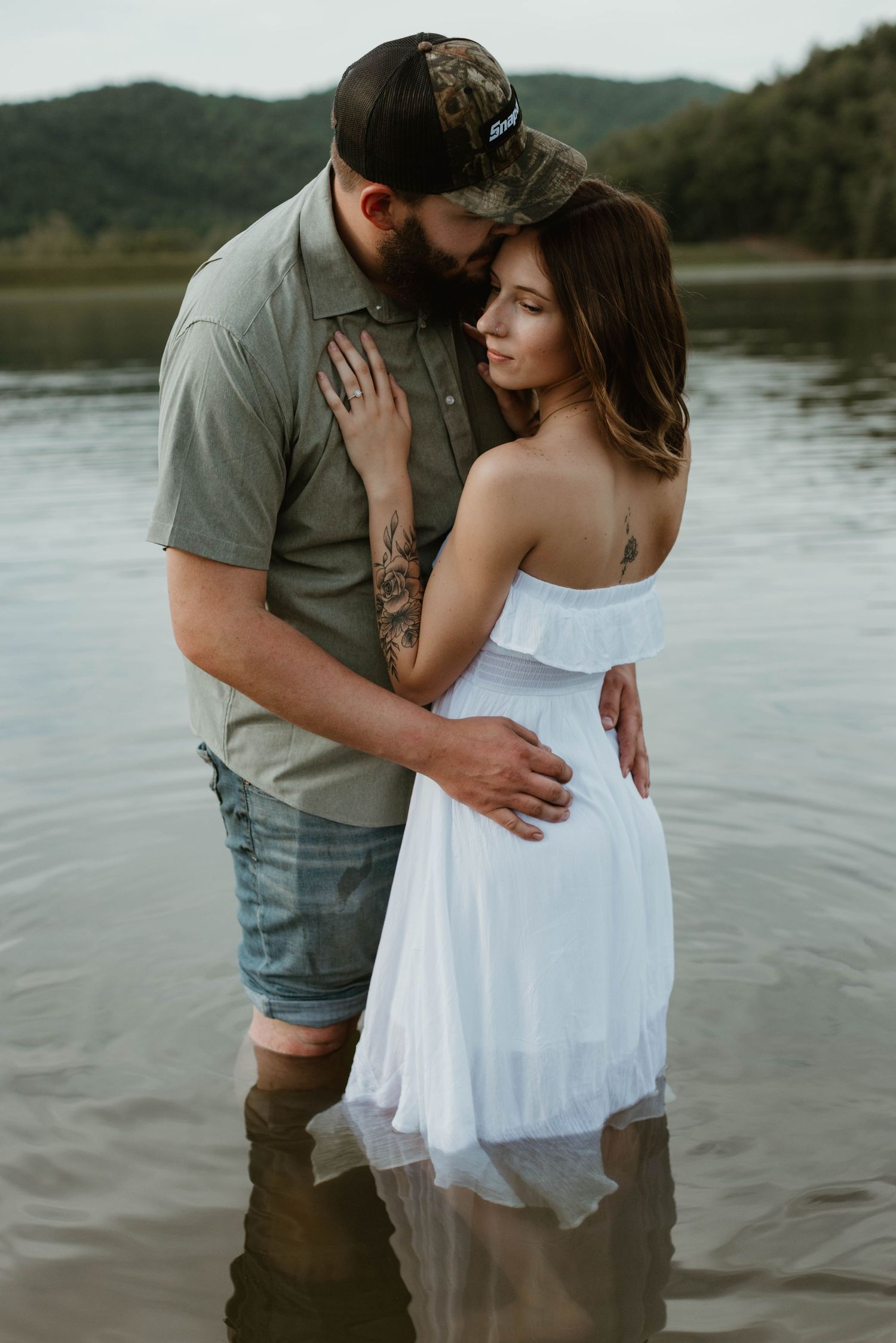 Romantic couple embracing in shallow water during sunset photoshoot.