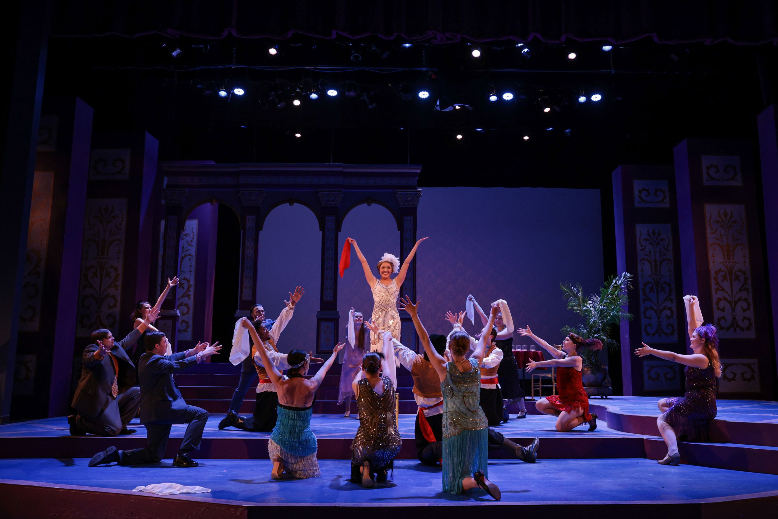 Performers dance on a dimly lit stage during a theatrical production with blue lighting effects. Theatre photography.