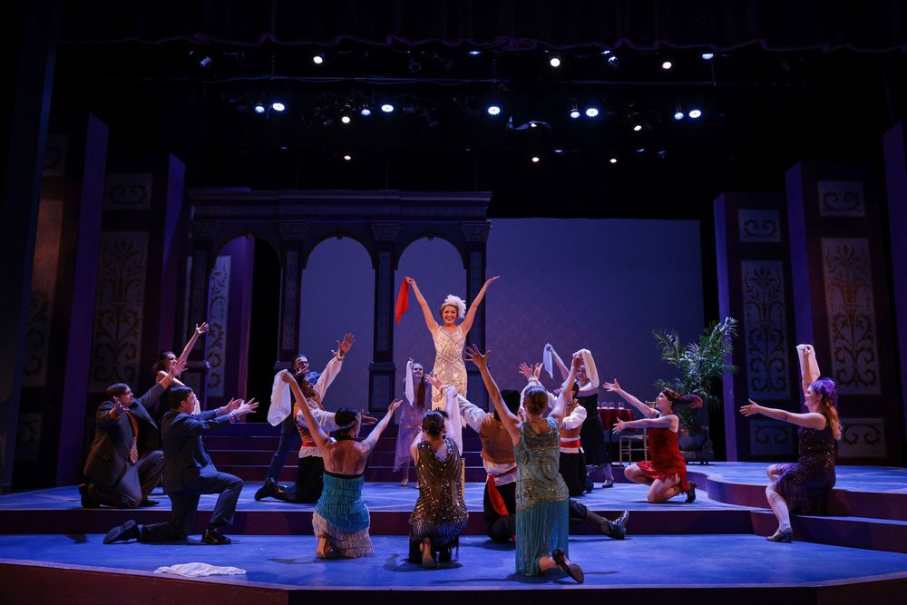 Performers dance on a dimly lit stage during a theatrical production with blue lighting effects. Theatre photography.