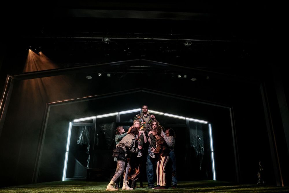 Dramatic stage performance with geometric light design and silhouetted figures.
