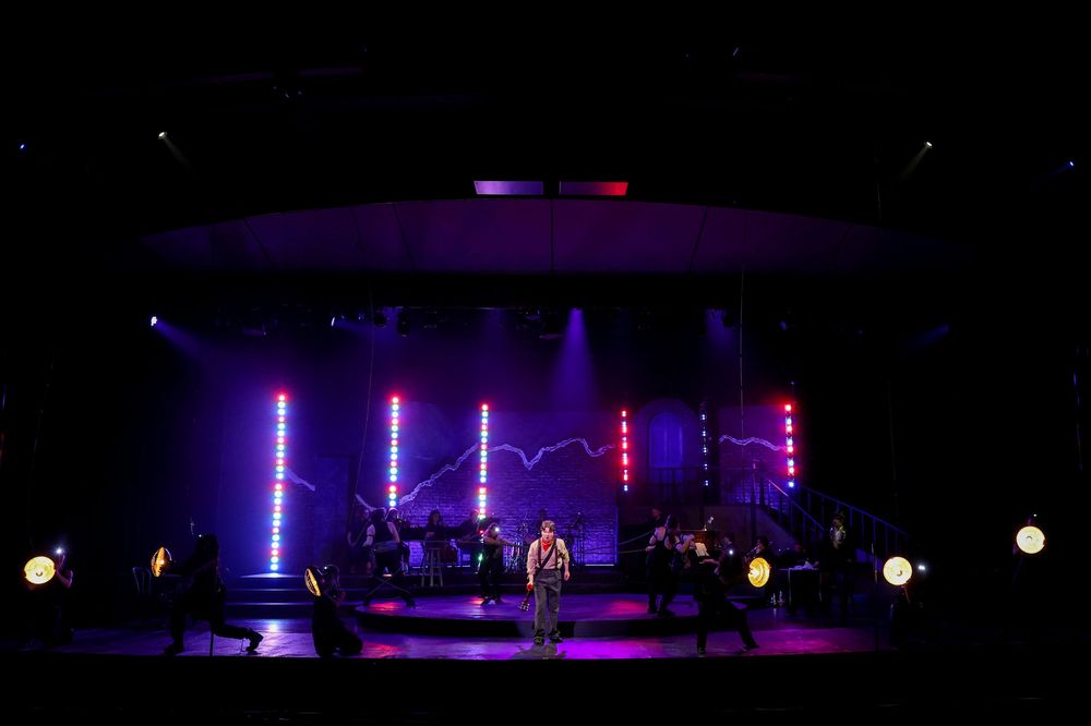 Concert stage lighting setup with blue and purple illuminated beams creating dramatic atmosphere in dark venue. Theatre photography.