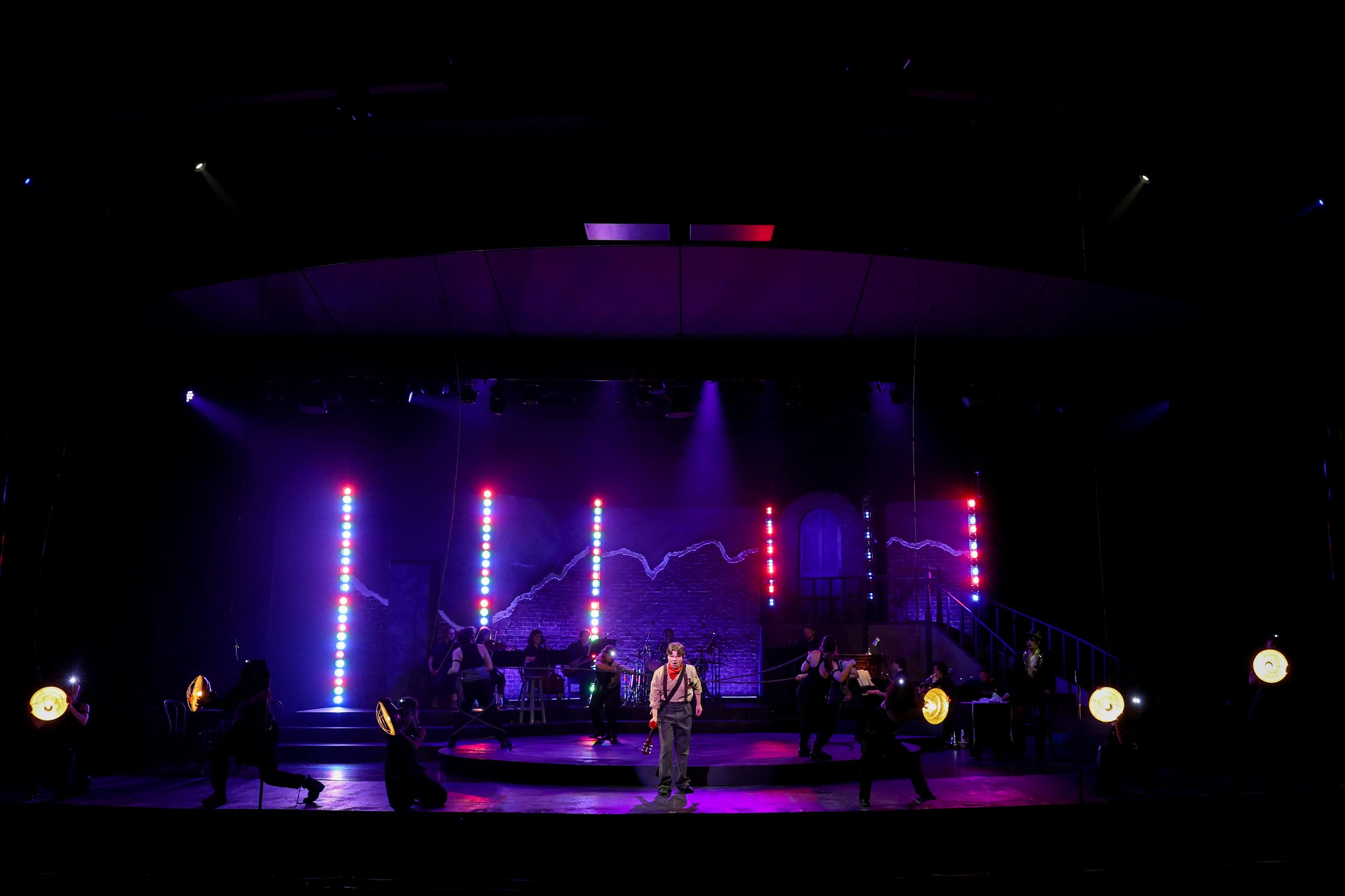 Concert stage lighting setup with blue and purple illuminated beams creating dramatic atmosphere in dark venue. Theatre photography.