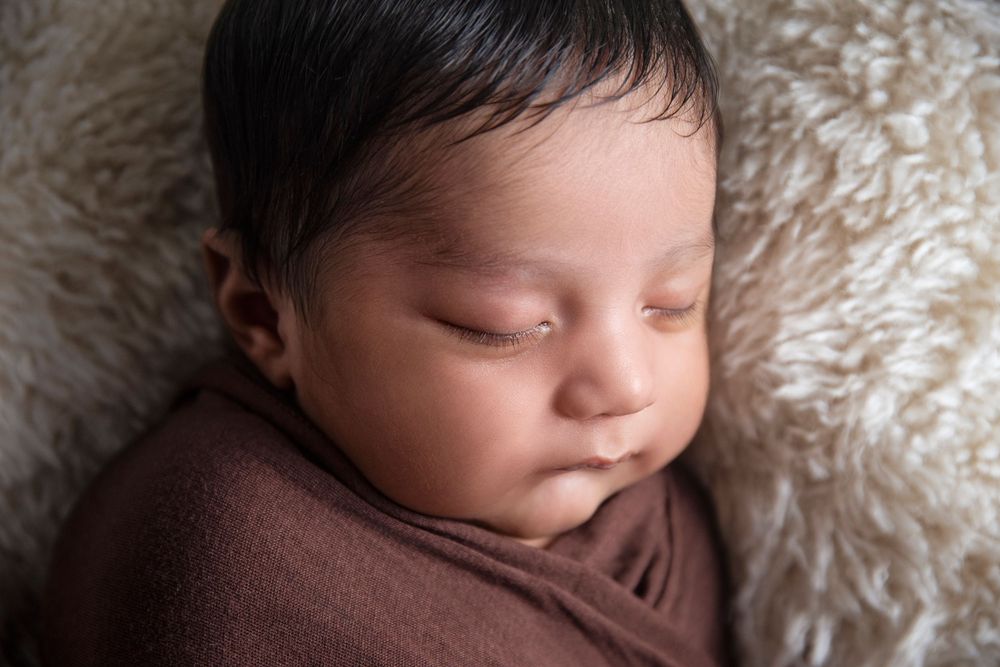 sleeping baby boy wrapped in a brown wrap