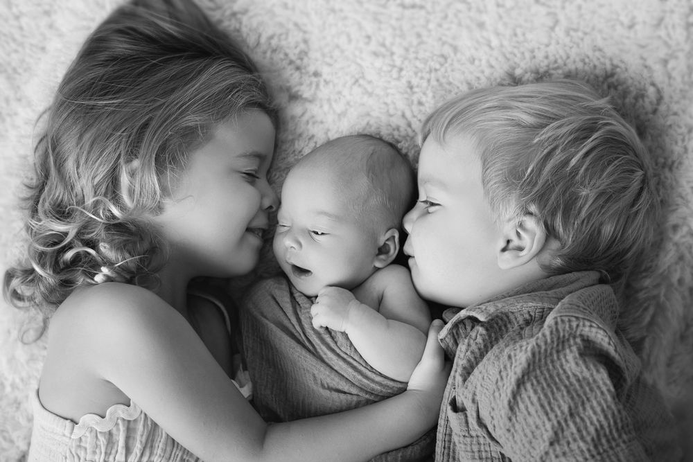 three siblings cuddling in their baby sisters newborn session on the Gold Coast with siblings always included