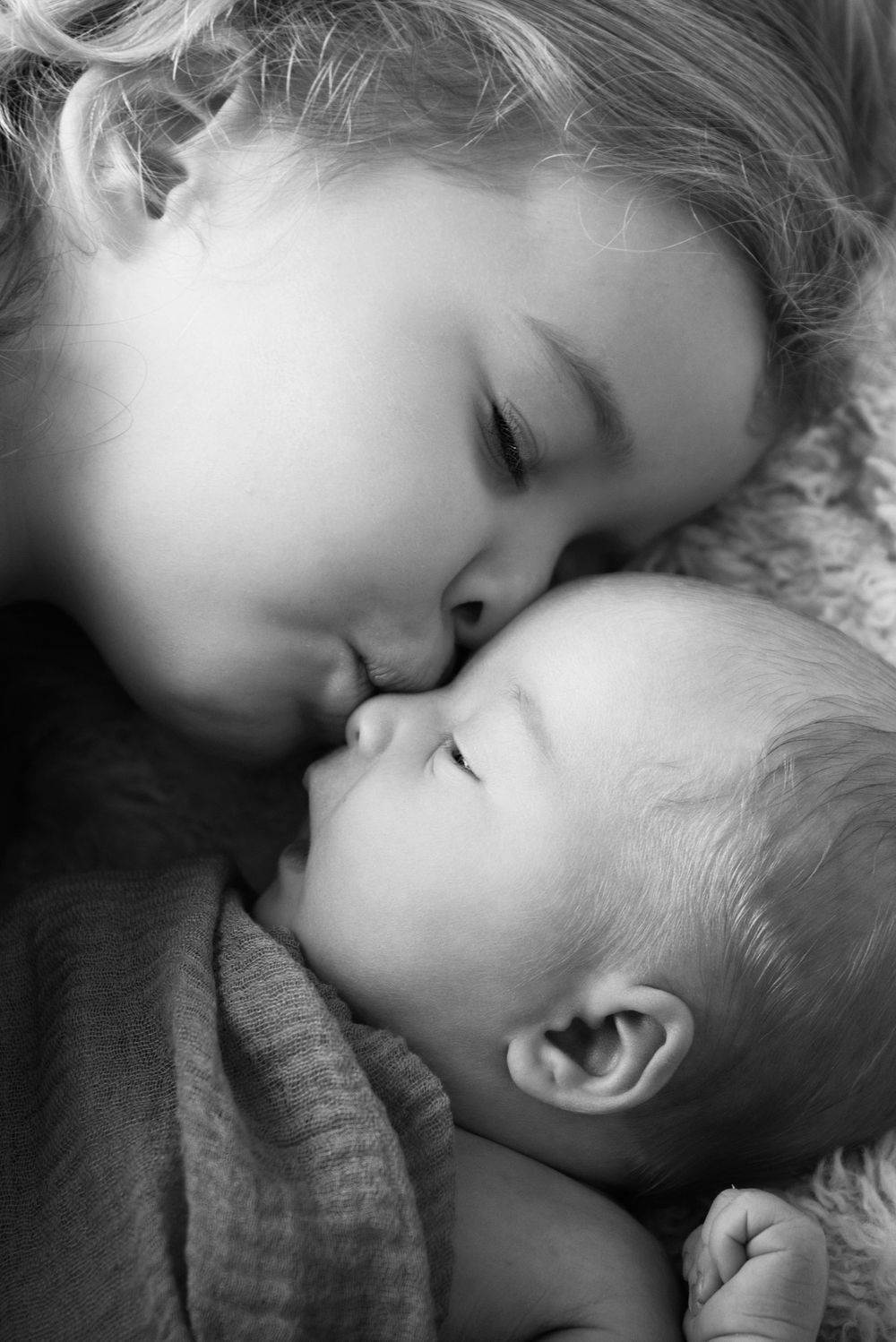 big sister kissing her new baby sister at her newborn session on the gold coast