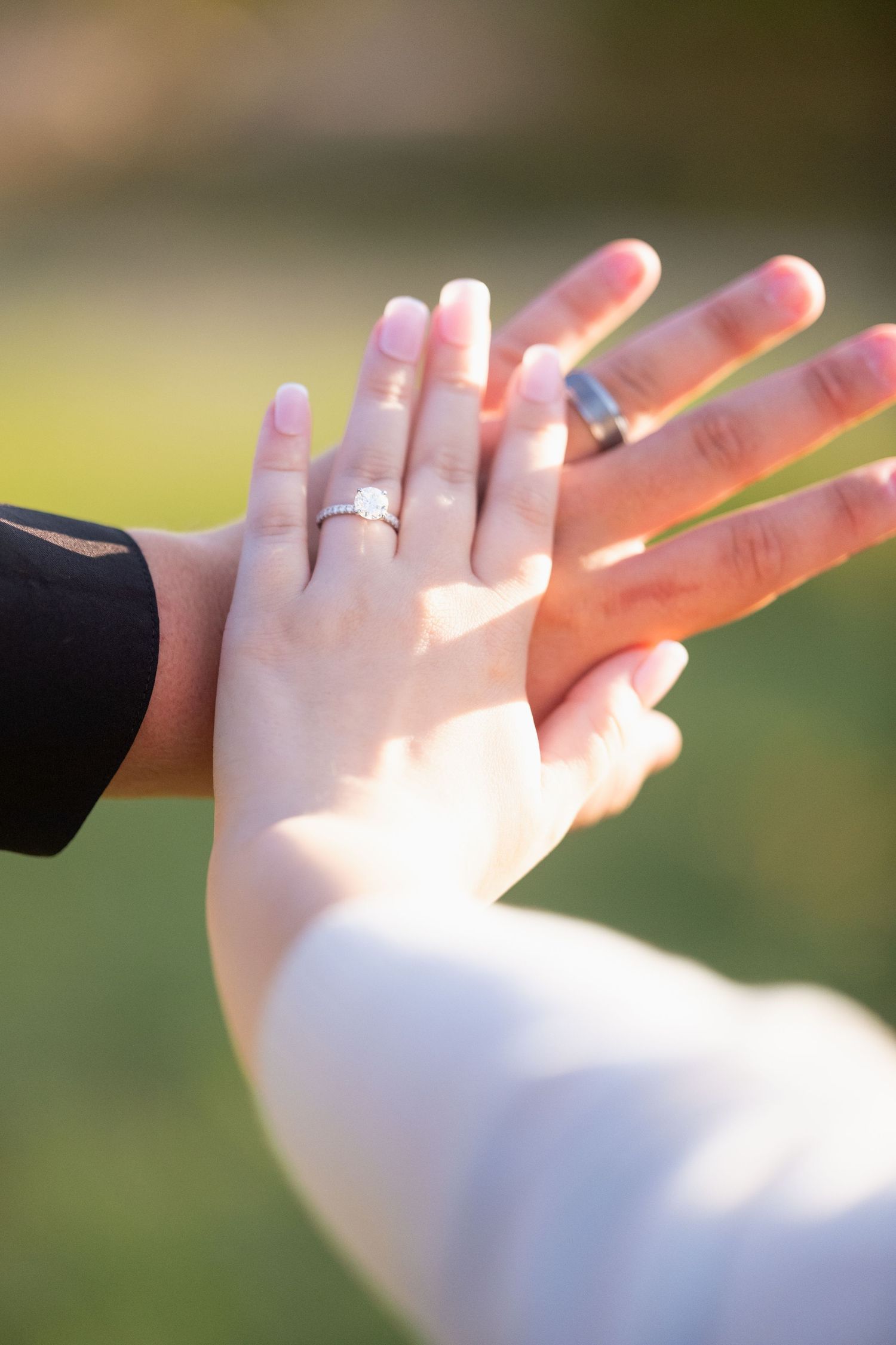 Close-up of couple's hands touching, showing diamond engagement ring and wedding band outdoors in Belton Texas
