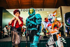 Three cosplayers pose near a food court, featuring armored Halo and Star Wars costumes at a convention.