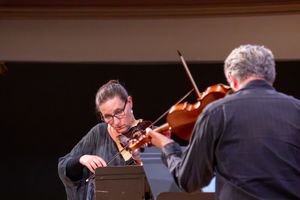 Two musicians playing violins together on stage during a classical music performance.