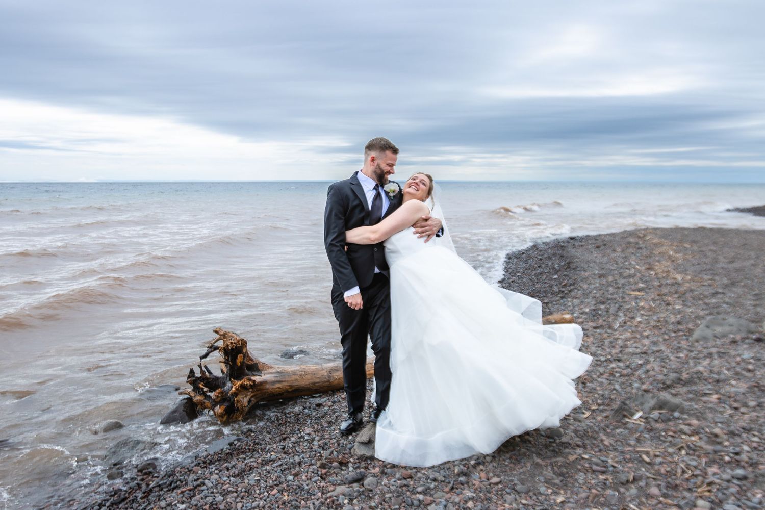 Bride and groom walk down the aisle under a rustic wooden gazebo surrounded by lush greenery with wedding party.