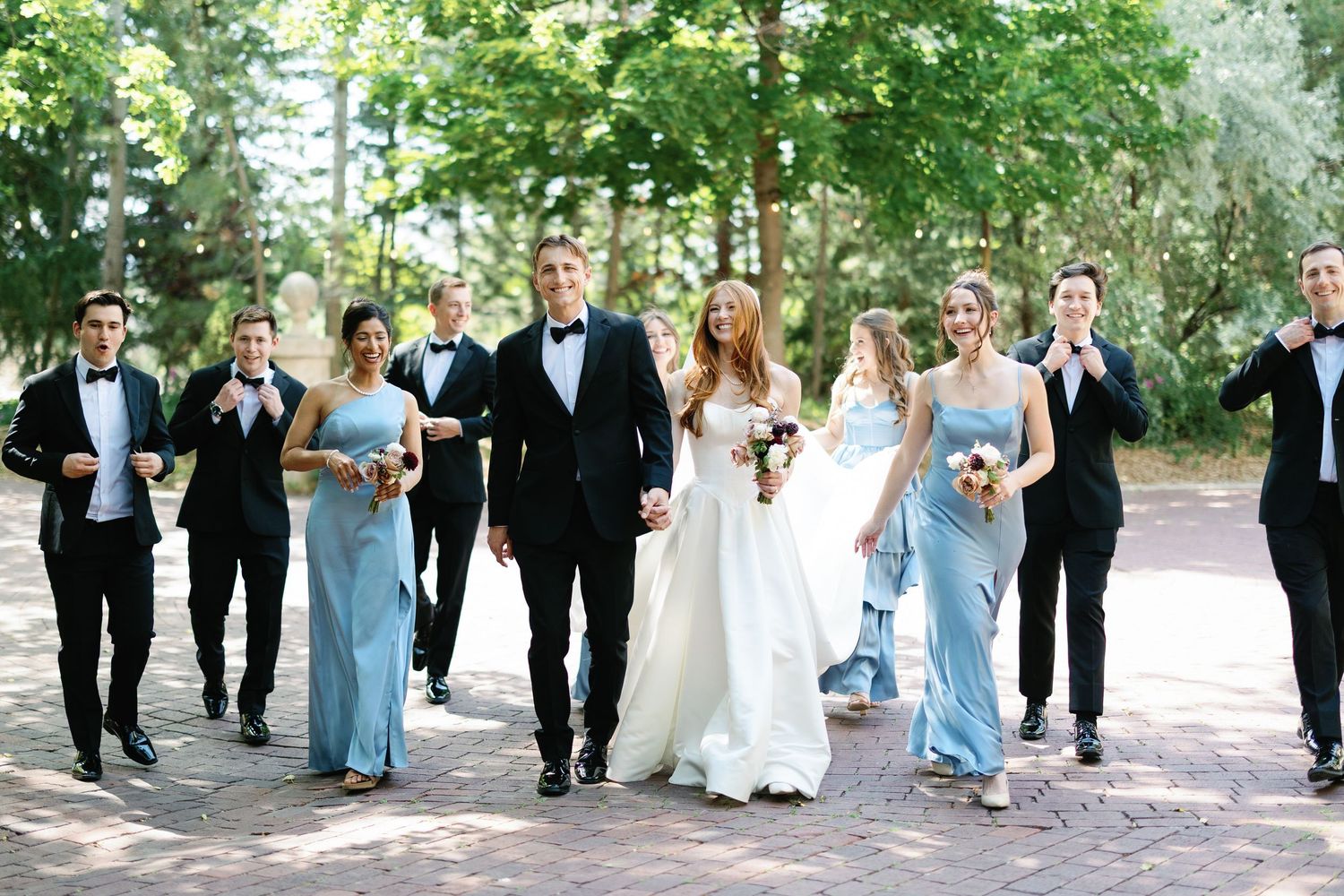 Bridesmaids holding rustic woven baskets filled with elegant white and green floral arrangements at a wedding ceremony.