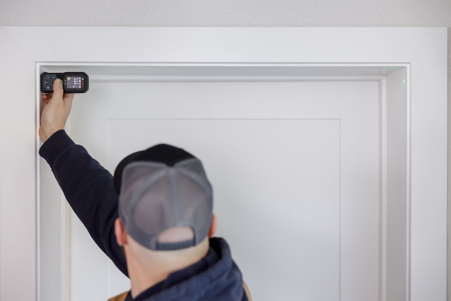 male contractor measuring width of door frame using electronic took linked to phone for lifestyle branding photo in Maple Valley, WA