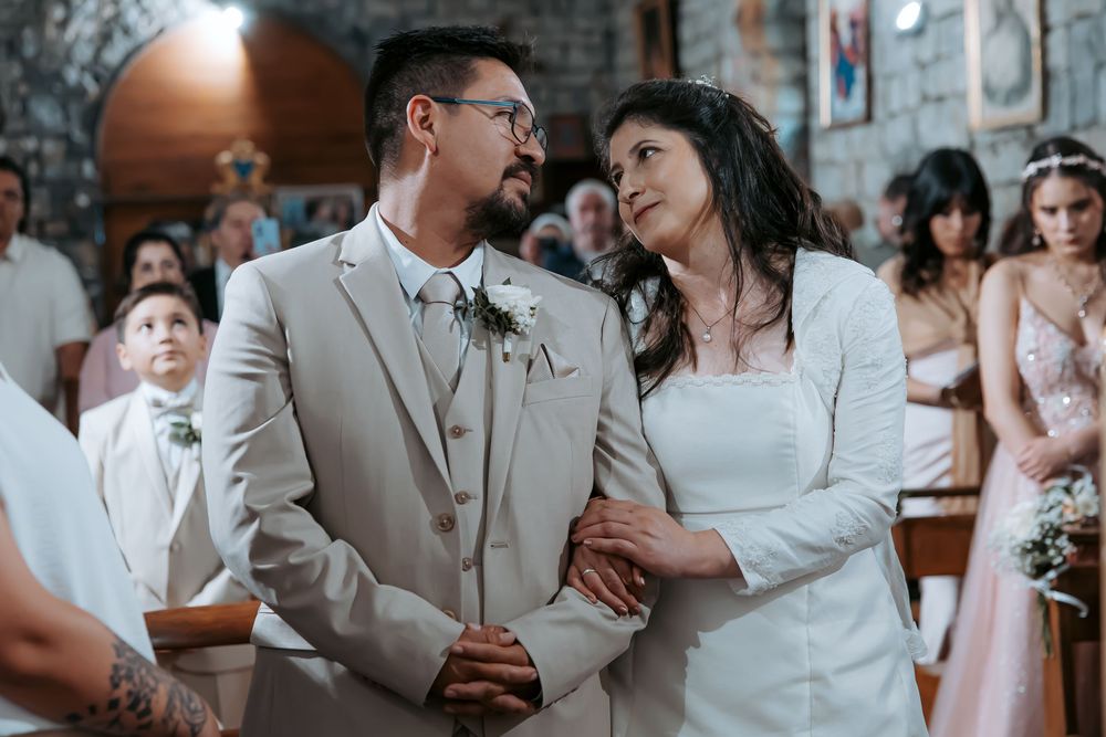 Bride and groom share a tender moment at the altar during their wedding ceremony inside a stone church.