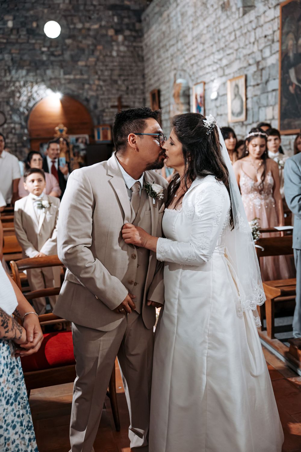 Bride and groom sharing a kiss at the altar during their church wedding ceremony, surrounded by guests in pews.
