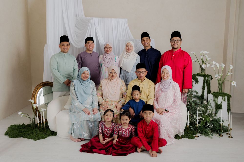Malaysian family in traditional Eid Baju Melayu and Baju Kurung attire posing together for a festive Hari Raya photo.