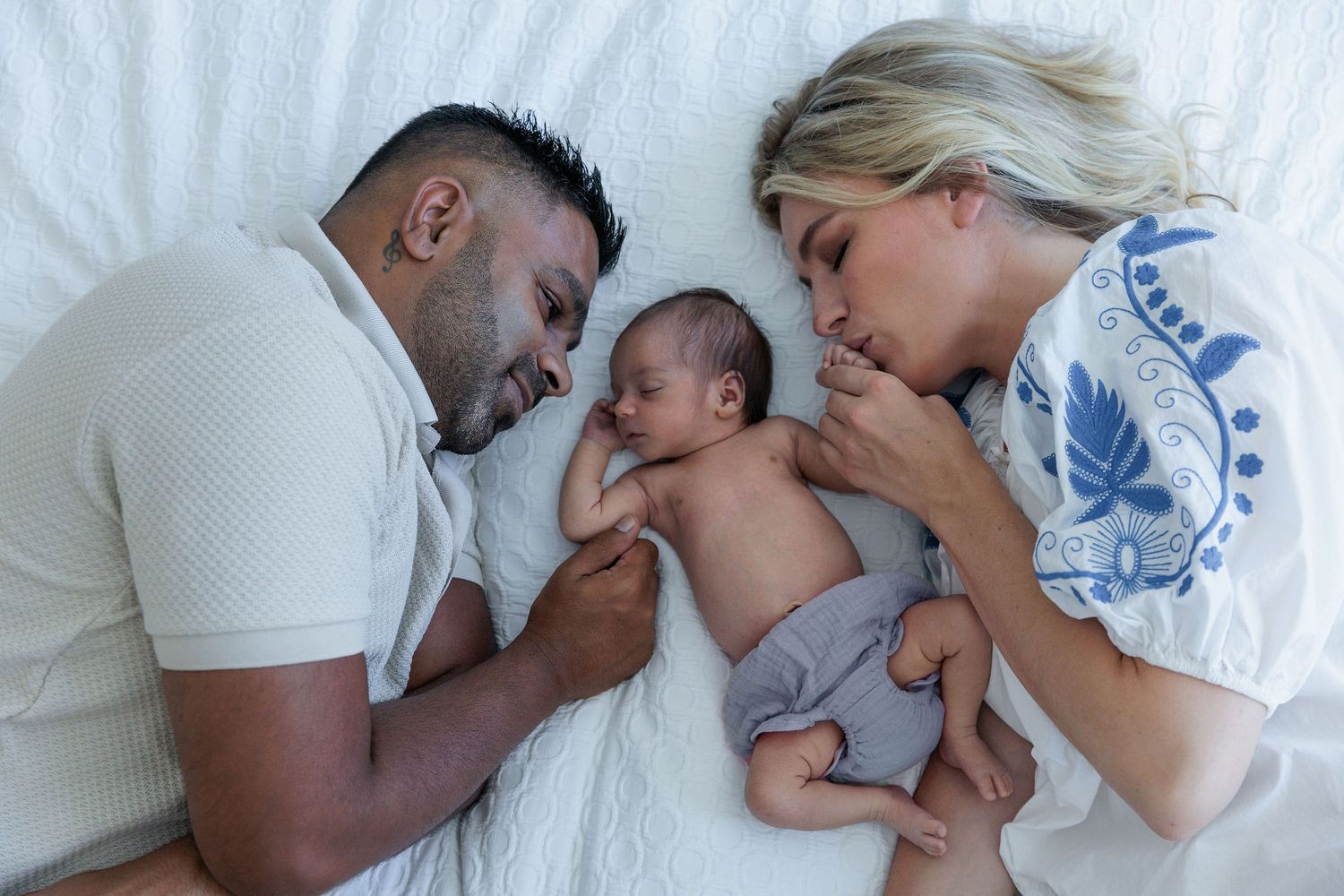Parents lying beside their newborn baby on the bed during a natural in-home newborn session