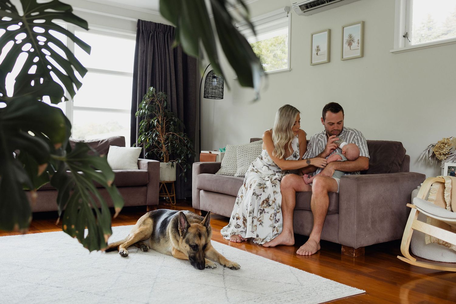New parents sitting together with their baby and dog during a lifestyle newborn session at home