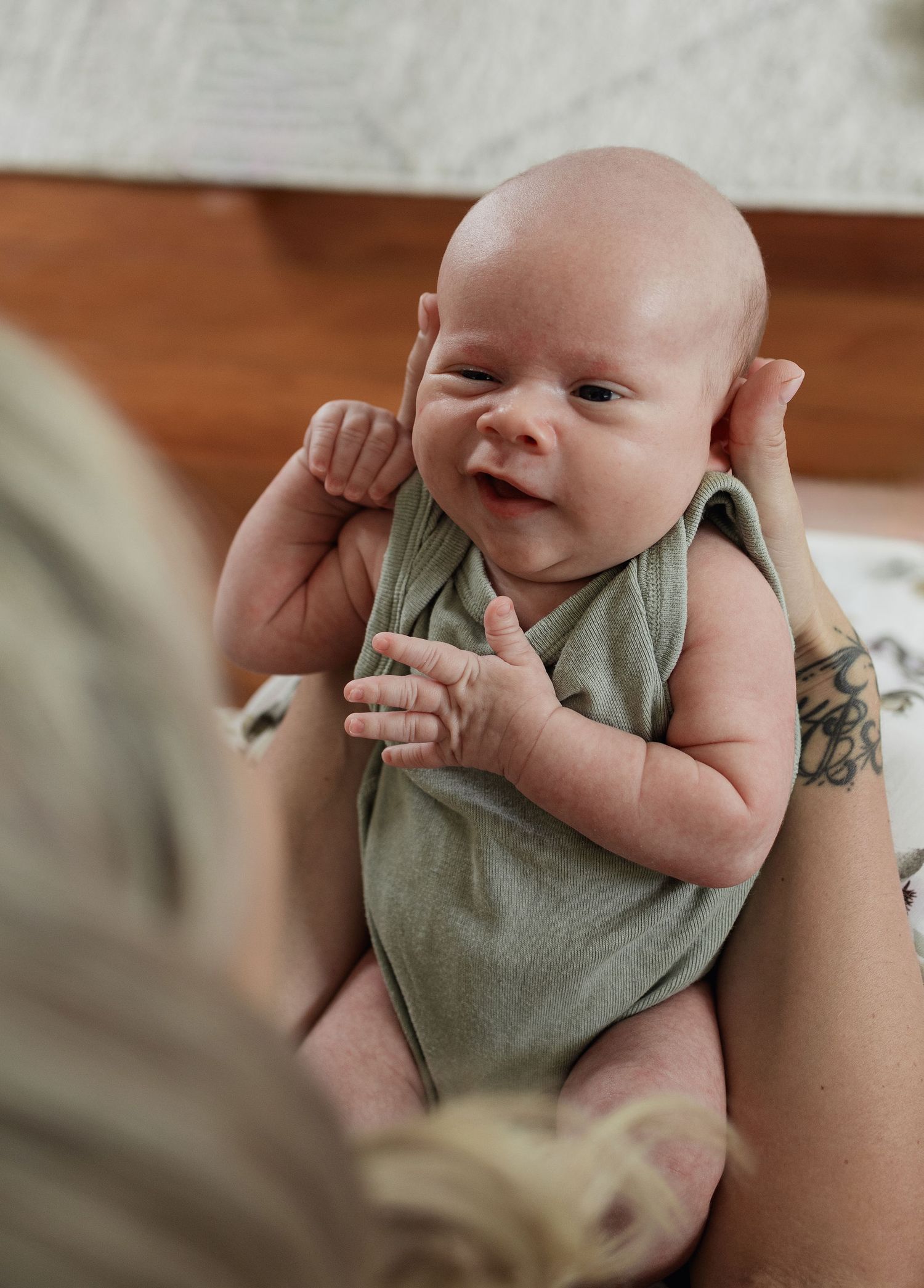 Newborn baby being gently held during an in-home lifestyle newborn session