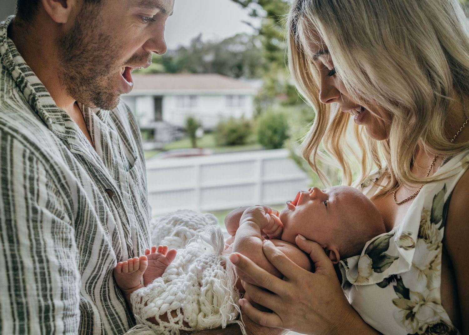 New parents smiling down at their newborn baby during an intimate in-home lifestyle session