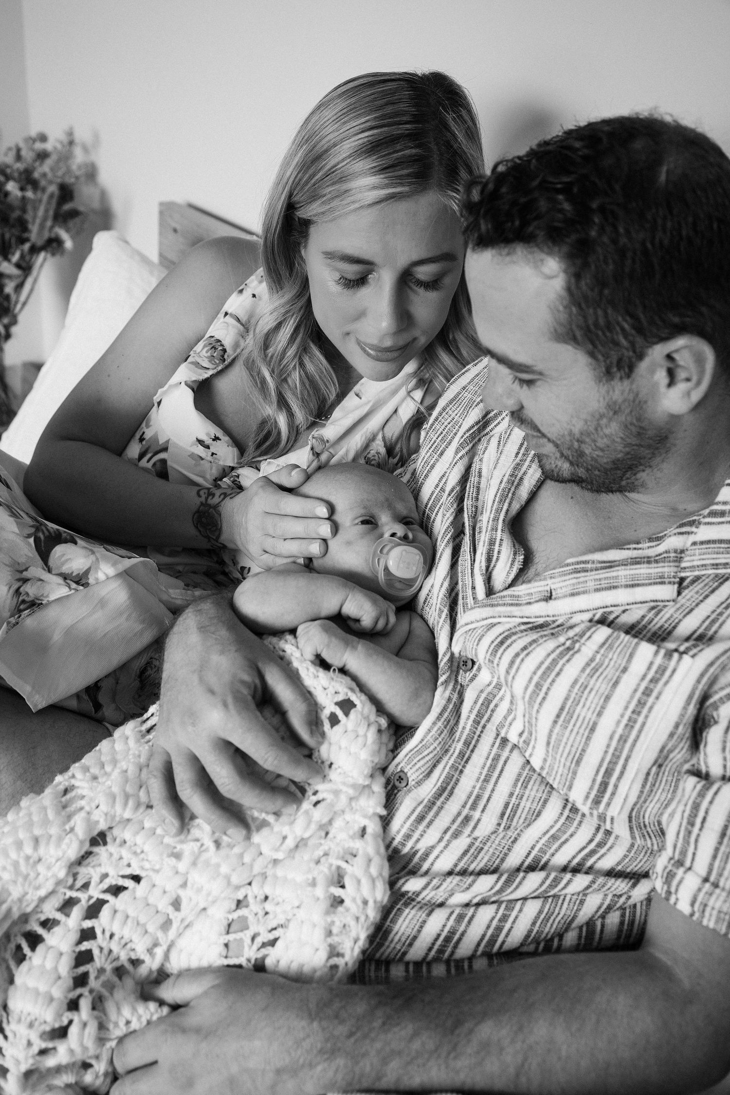 Black and white portrait of parents cuddling their newborn baby close together