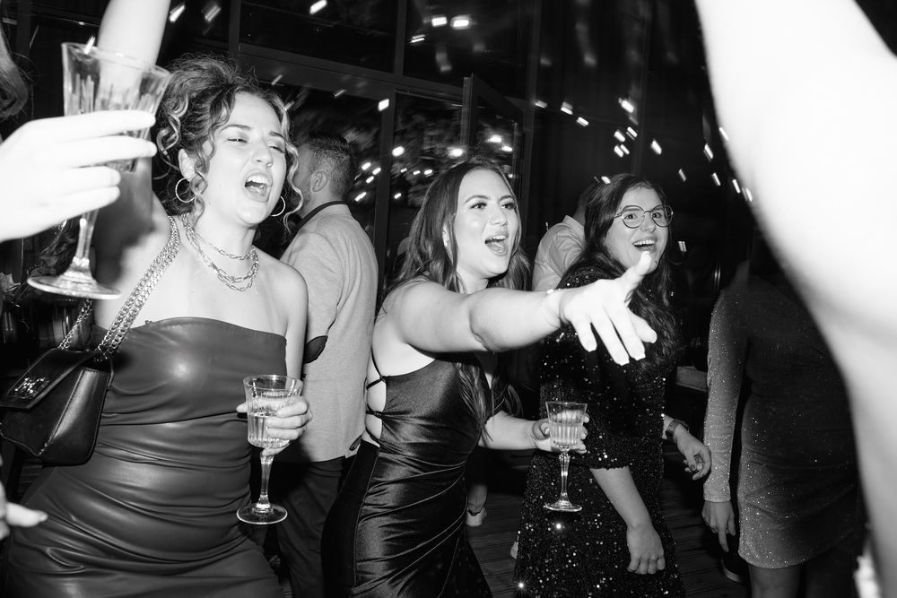 Guests celebrate with champagne and confetti on the dance floor at a lively wedding reception.