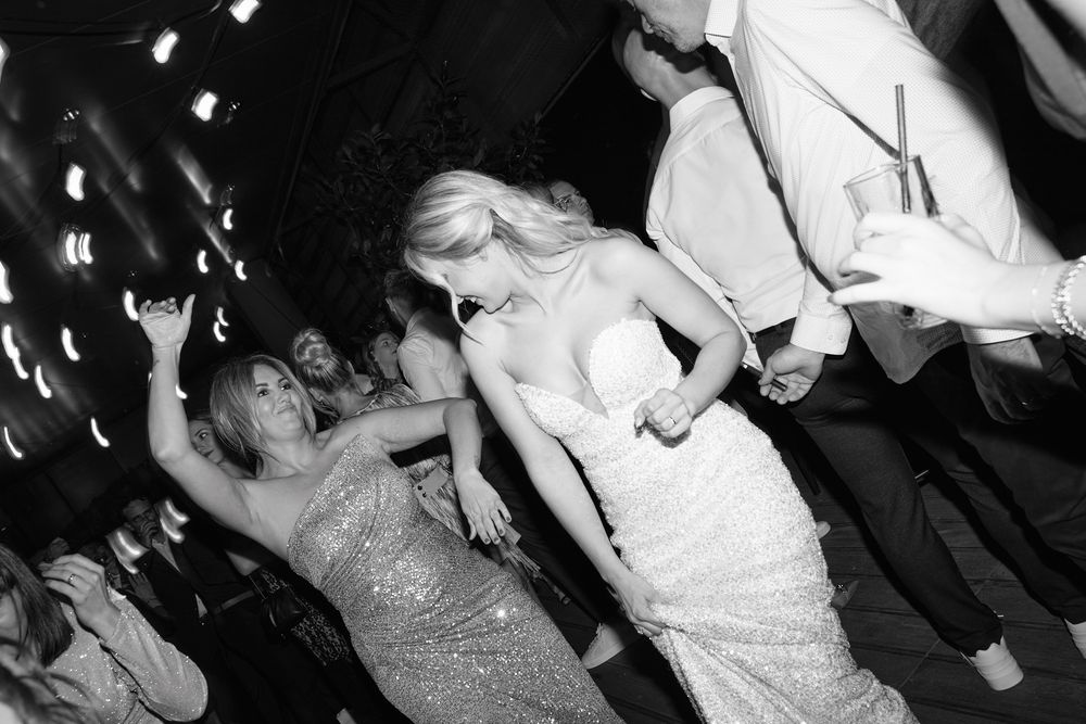 Black and white photo of elegantly dressed women dancing at a glamorous party or formal event.