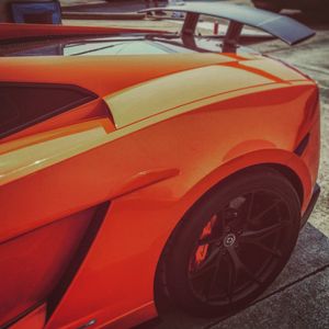 Close-up of a vibrant orange Lamborghini Aventador supercar showcasing its sleek body lines and black alloy wheel.