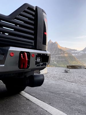 Heavy-duty truck rear bumper with red accents and auxiliary lights parked near scenic mountain vista.
