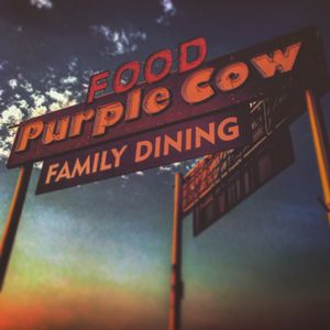 Vintage Purple Cow Food Family Dining restaurant sign against a dramatic sunset sky.
