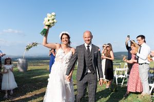 Joyful bride and groom walk back down the aisle after their outdoor vineyard wedding ceremony.