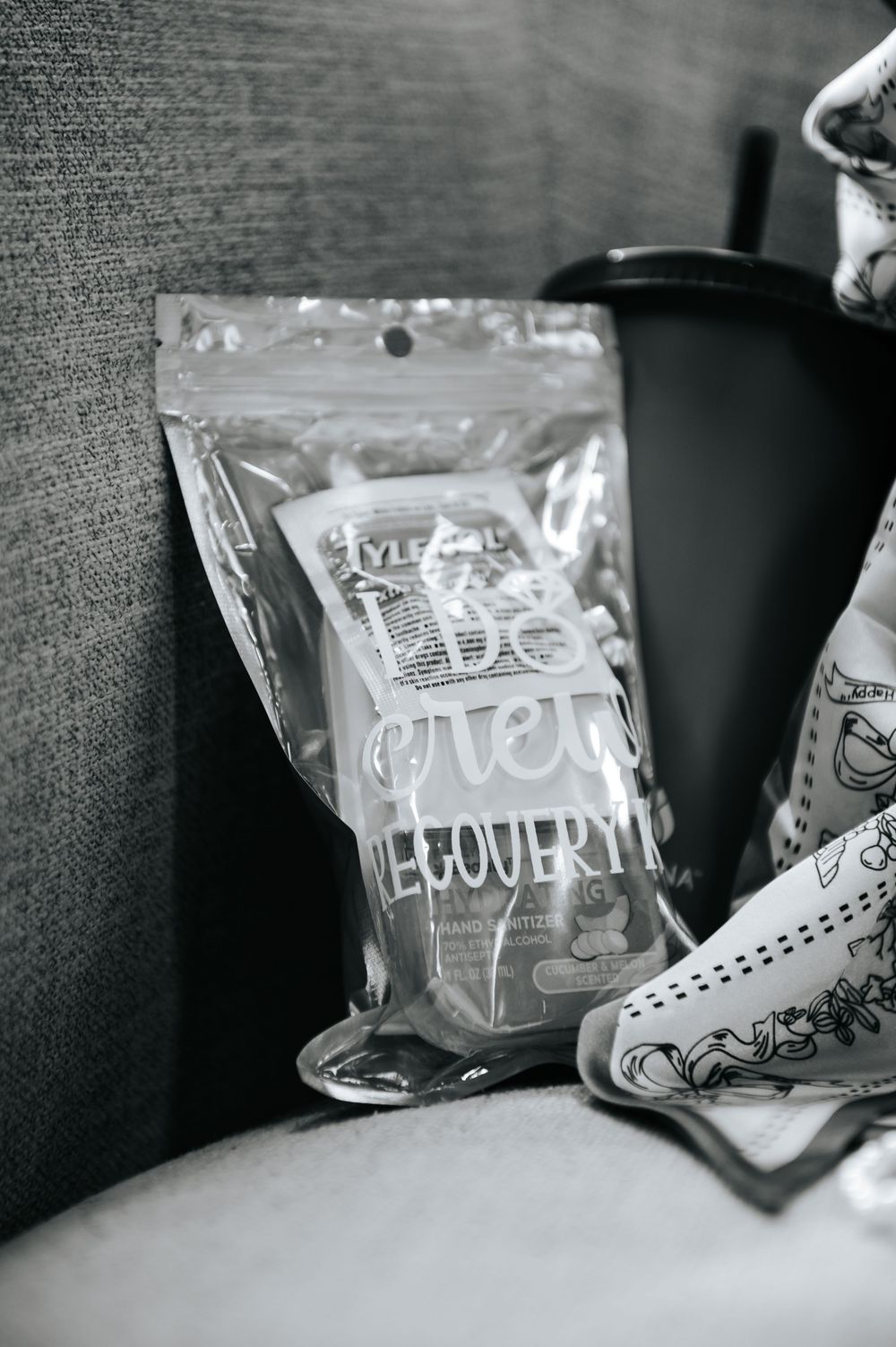 Black and white photo of a recovery kit bag placed on a gray sofa next to a cup.