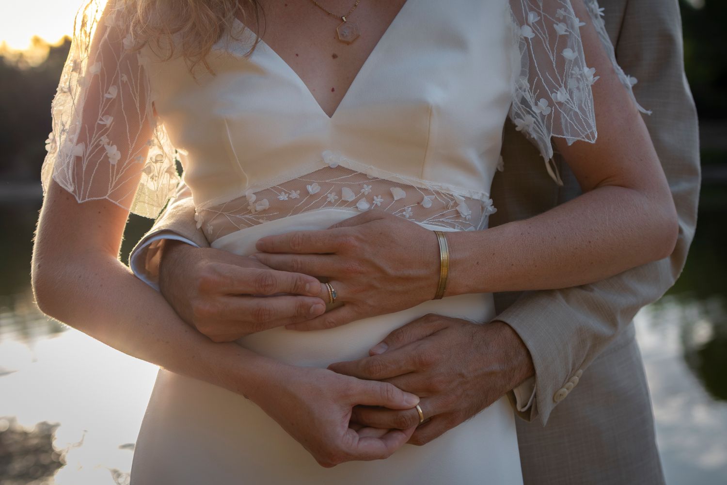 Mariés enlacés en gros plan, mains croisées sur la taille de la mariée en dentelle, séance à Lyon