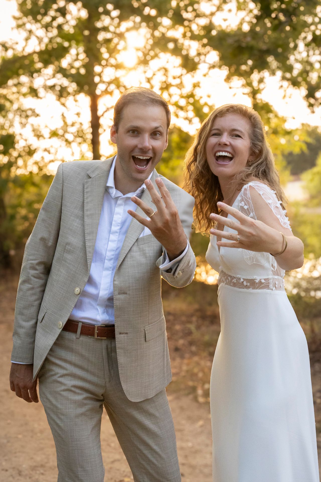 Couple de mariés riant aux éclats en pleine nature, lumière dorée du soir, séance mariage à Lyon