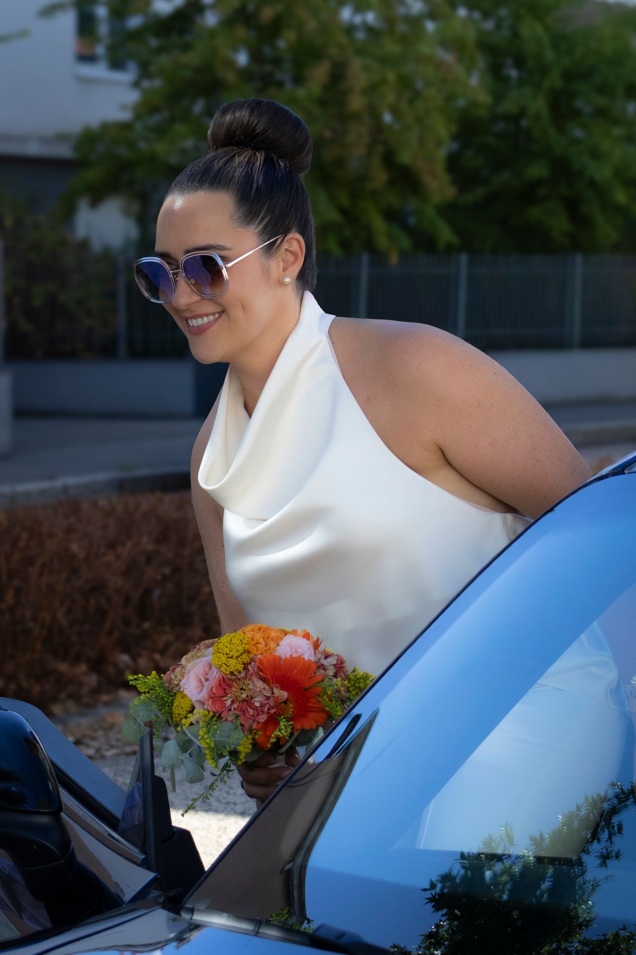 Mariée en tenue blanche tenant un bouquet coloré, entrant dans une voiture noire, mariage civil à Lyon