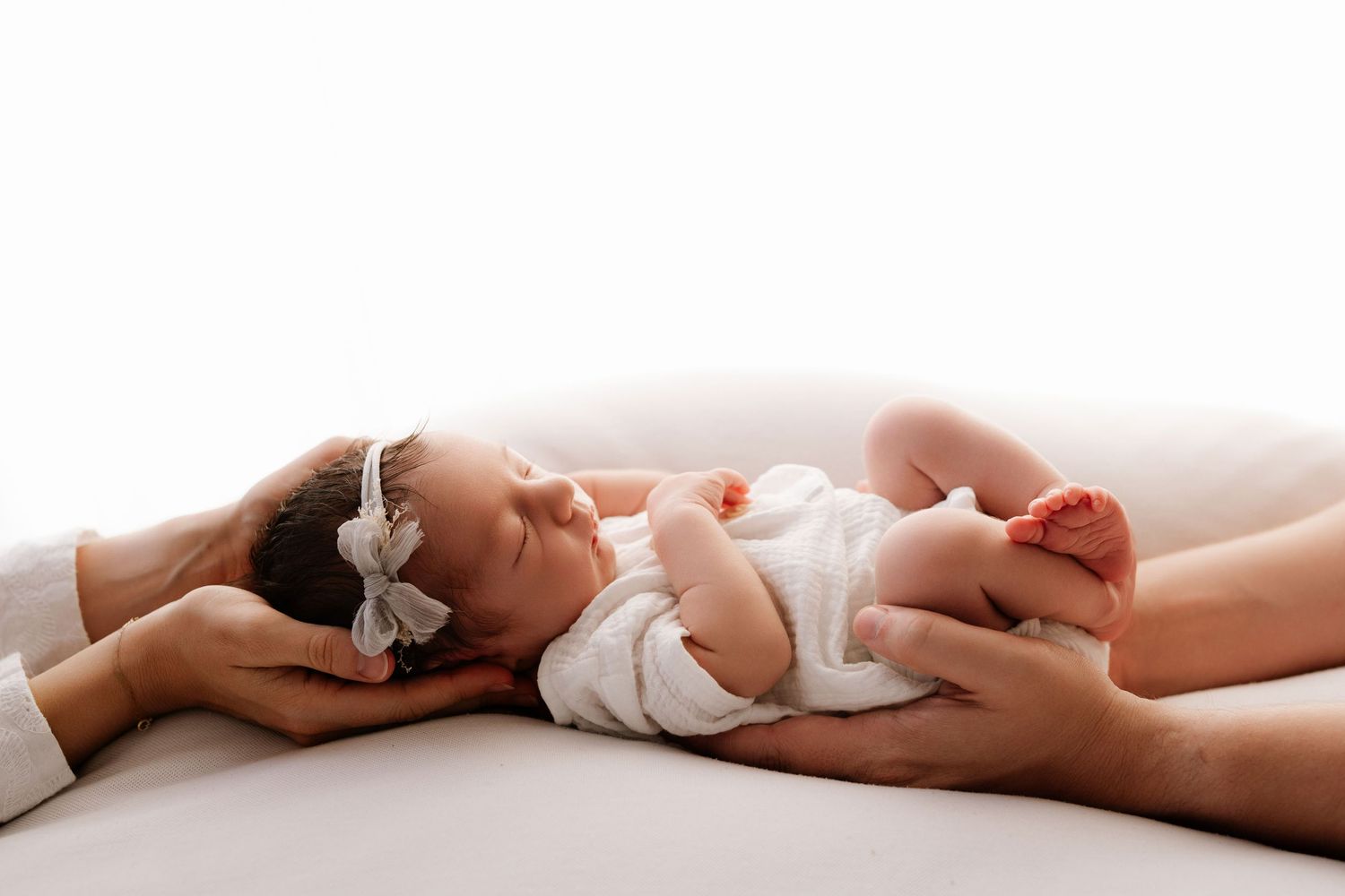 Man in white shirt kissing pregnant woman's belly in a bright, minimalist setting.