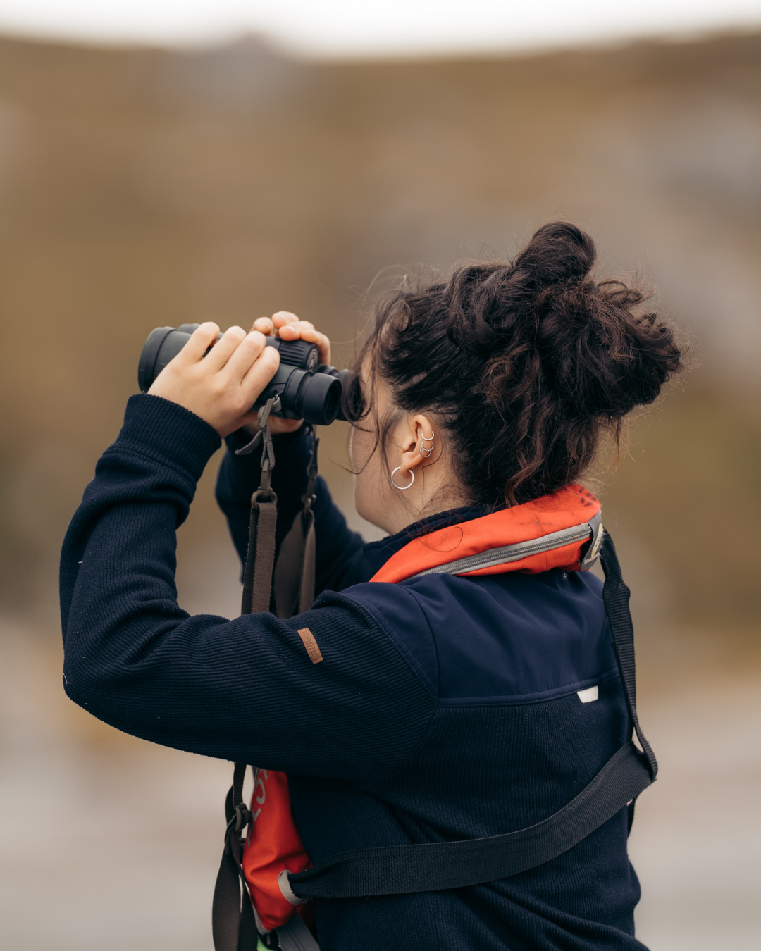 femme qui observe aux jumelles depuis les terres du spitberg